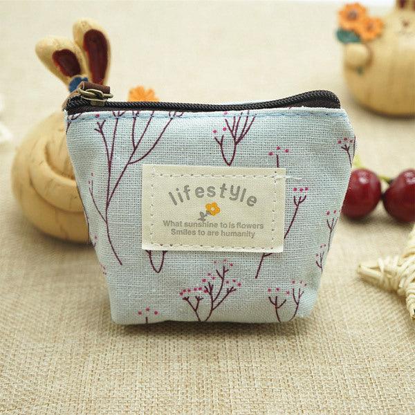 Small fabric coin purse with floral print, zipper closure, and lifestyle quote patch on beige background