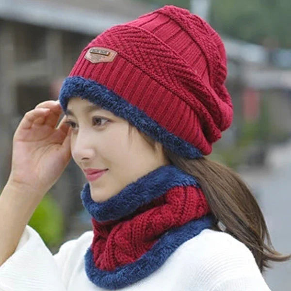 Woman wearing a red knit beanie and matching neck warmer with blue fleece trim outdoors