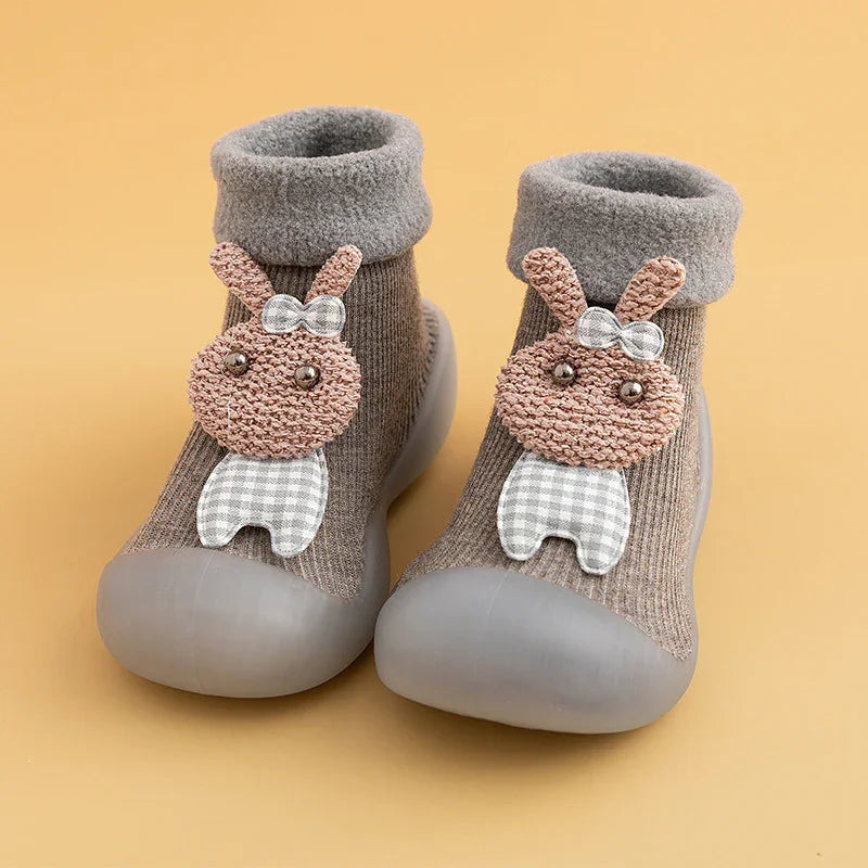 Brown toddler socks with gray soft soles and cute bunny decoration on beige background