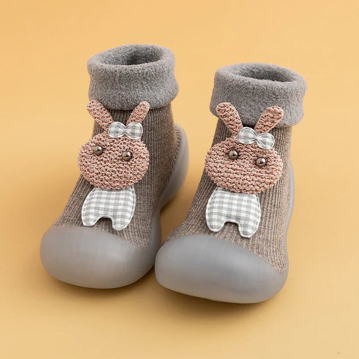 Brown toddler socks with gray soft soles and cute bunny decoration on beige background