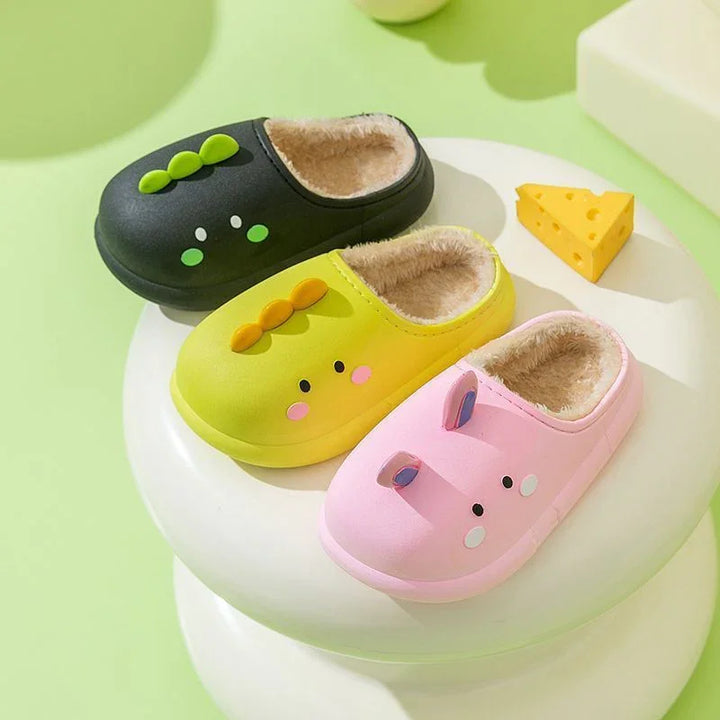 Three colorful kids slippers with cartoon faces and soft fur lining on white stool with yellow cheese toy