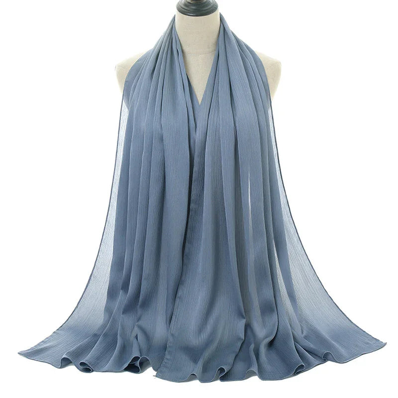 Light blue pleated chiffon scarf draped on mannequin, soft and elegant fashion accessory