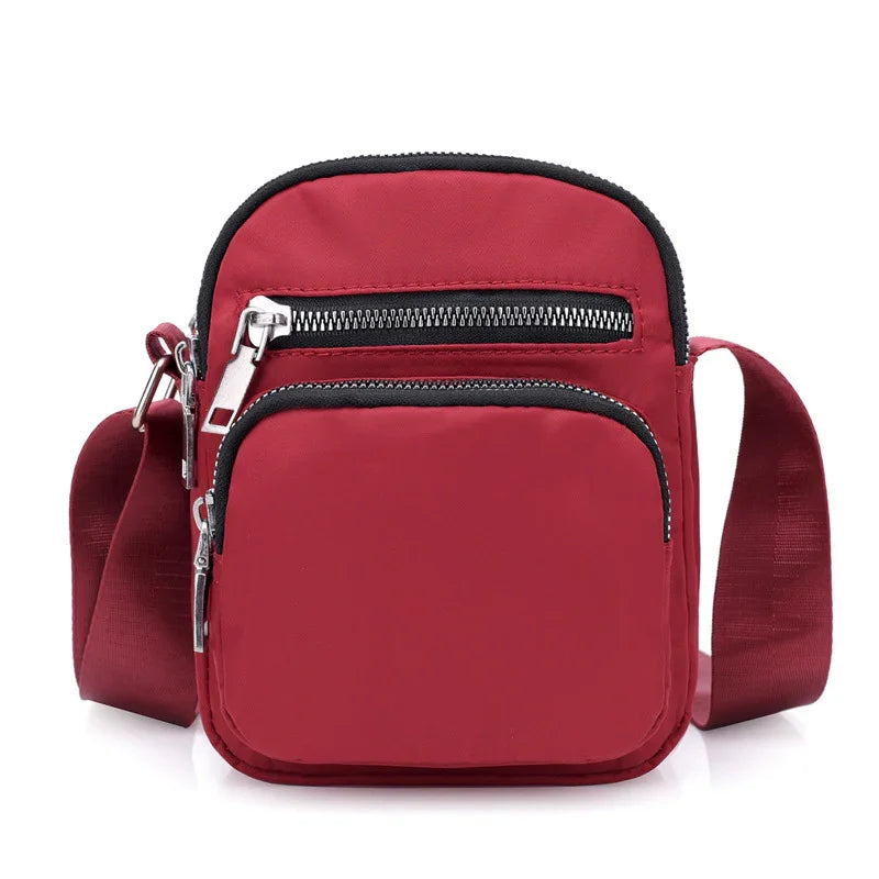 Compact red crossbody bag with two zippered compartments and adjustable shoulder strap