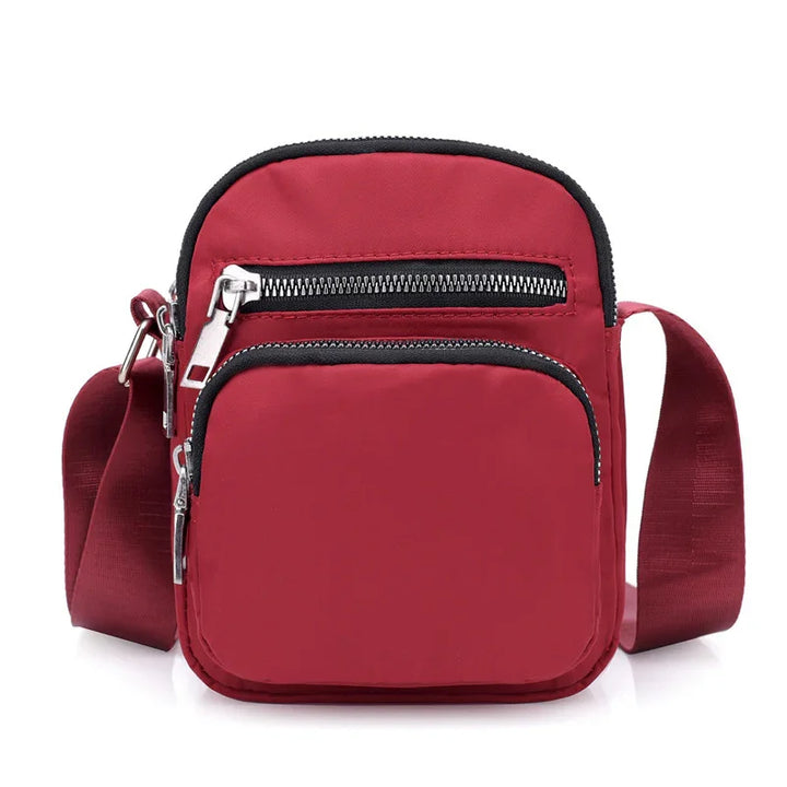Compact red crossbody bag with two zippered compartments and adjustable shoulder strap