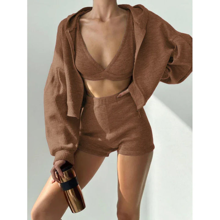 woman wearing brown ribbed knit hoodie, bralette, and shorts set holding a copper travel mug
