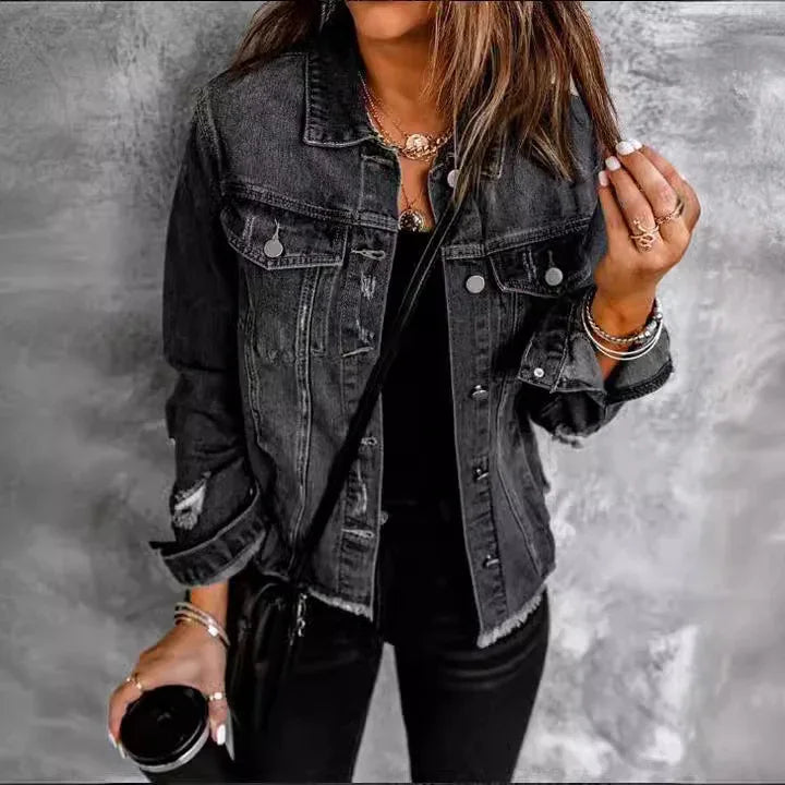 Woman wearing a black distressed denim jacket with rolled sleeves and layered gold jewelry