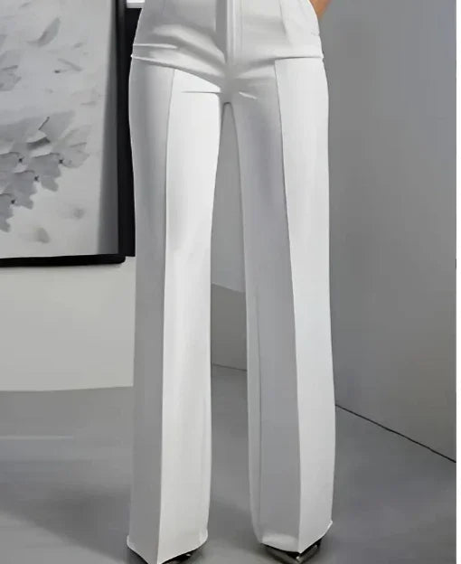Woman wearing high-waisted white wide-leg pants in minimalist indoor setting with abstract wall art