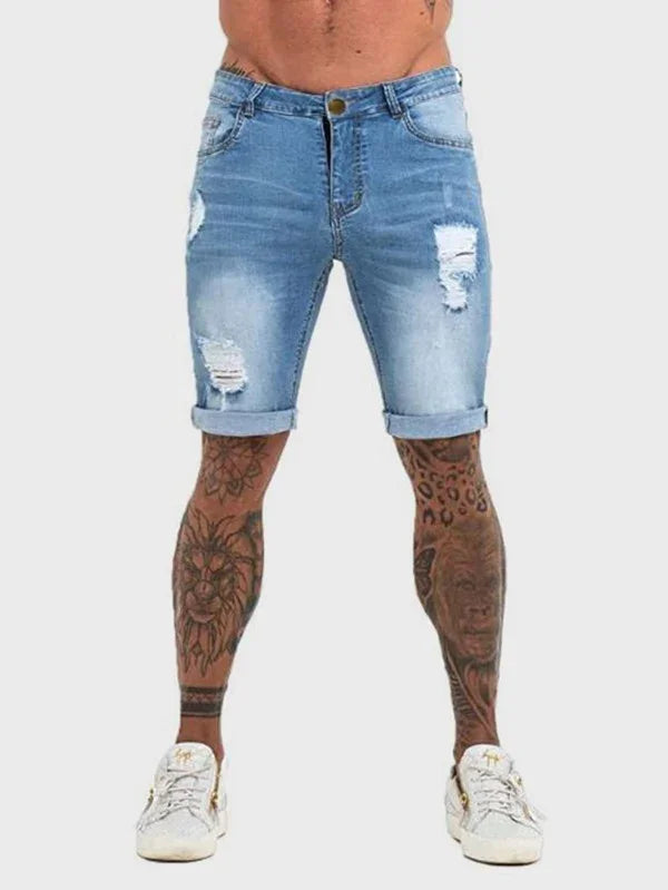 Men's light blue distressed denim shorts with rolled cuffs worn by tattooed legs and white sneakers