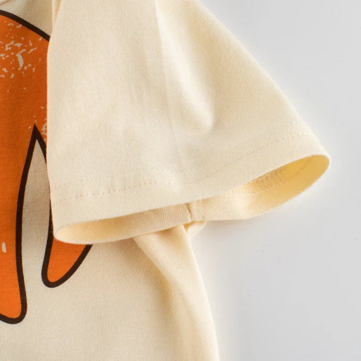 Close-up of cream-colored cotton t-shirt sleeve with partial orange and black graphic design