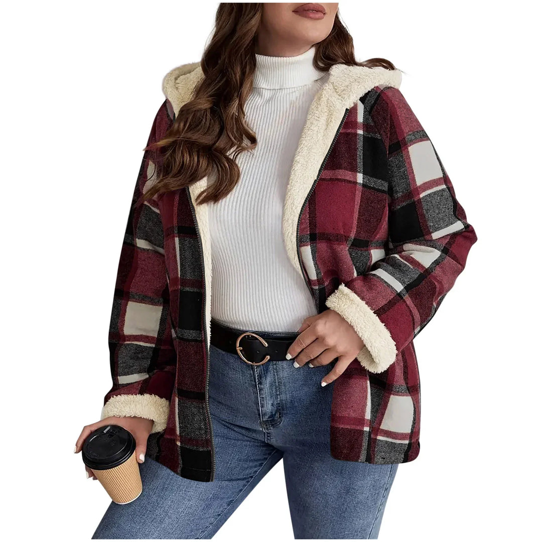 Woman wearing red and black plaid sherpa-lined jacket with white turtleneck and blue jeans holding coffee cup