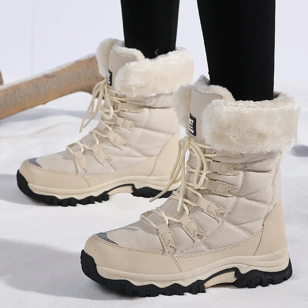 Cream lace-up winter boots with faux fur lining and black rugged soles on snow