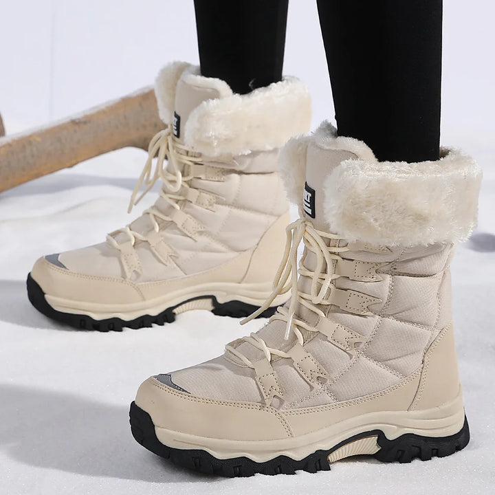 Cream lace-up winter boots with faux fur lining and black rugged soles on snow