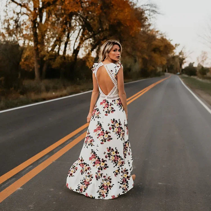 Woman in white floral maxi dress with open back standing on empty road with autumn trees