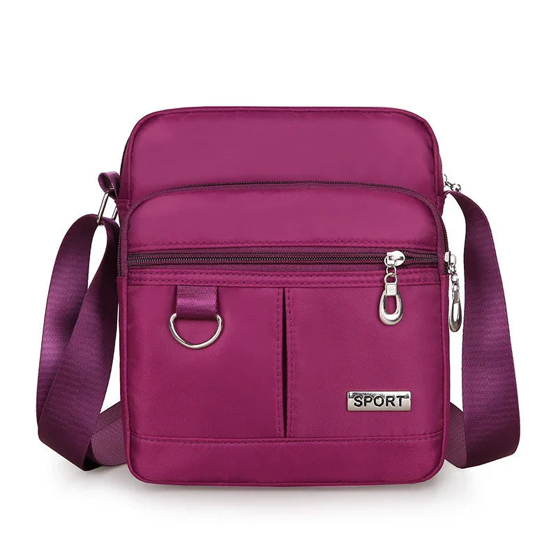 Compact purple crossbody sport bag with front zip pockets and adjustable shoulder strap