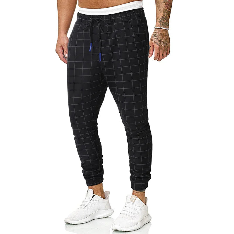 Men's black jogger pants with white grid pattern, white waistband, drawstring, and white sneakers