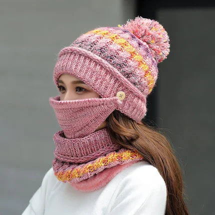 Woman wearing a knitted pink winter hat with pom-pom and matching face mask and scarf