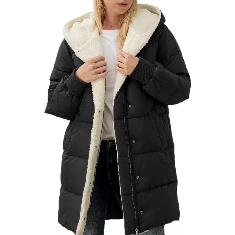 Woman wearing a black puffer coat with white sherpa lining and hood, paired with jeans and white shirt