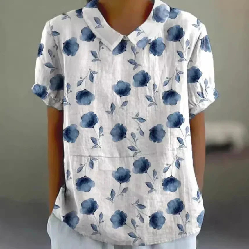White short-sleeve blouse with blue floral print and rounded collar on person
