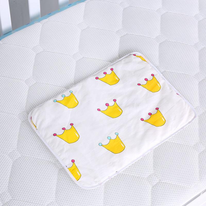 White rectangular baby pillow with yellow crown patterns on a textured white mattress