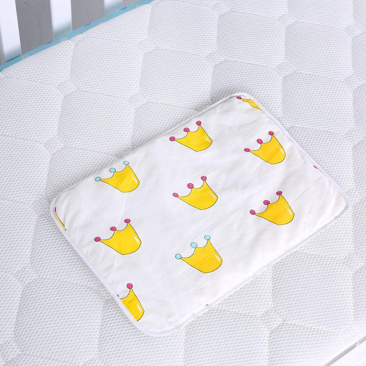 White rectangular baby pillow with yellow crown patterns on a textured white mattress