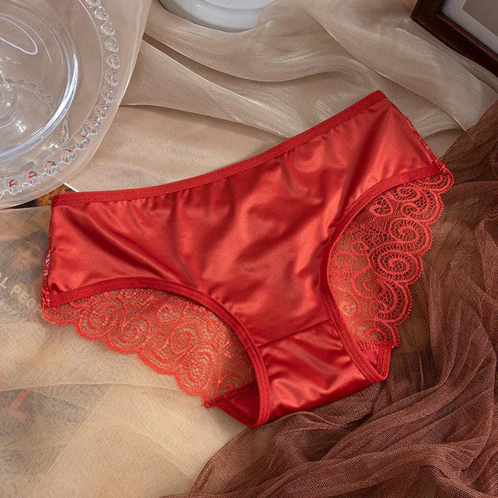 Red satin women's underwear with lace trim on sheer fabric background
