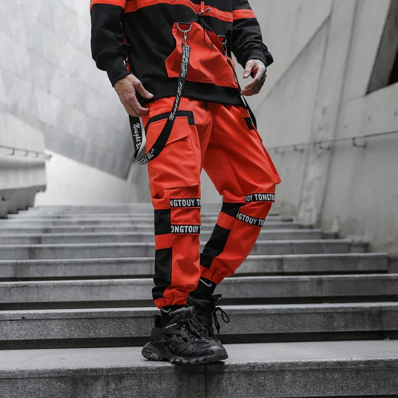 Person wearing orange and black cargo pants with black sneakers standing on gray stairs