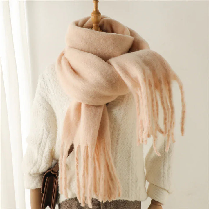 Soft pink fringed scarf wrapped around mannequin wearing white textured sweater and brown tweed skirt