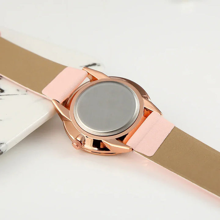 Rose gold watch case with pink leather strap, back view on white surface