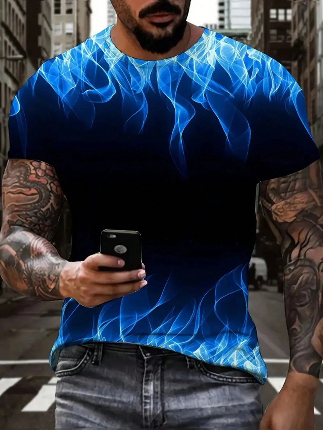 Man with tattoos wearing black t-shirt with blue flame design using smartphone in urban street