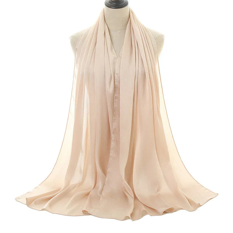 Elegant beige chiffon scarf draped on dress form against white background