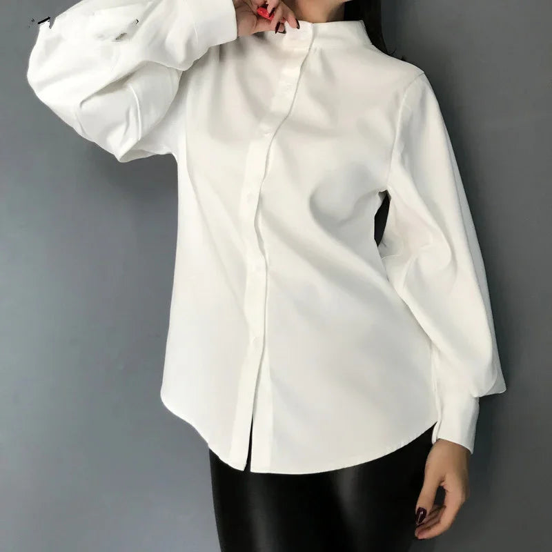 Woman wearing stylish white long-sleeve blouse with high collar and black leather pants