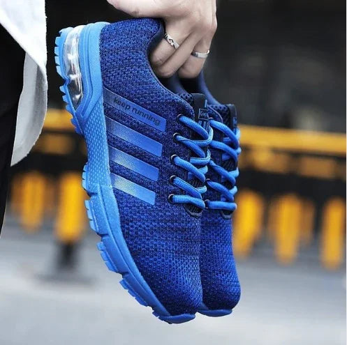 Blue knit running shoes with blue laces and cushioning sole held by hand, featuring keep running text