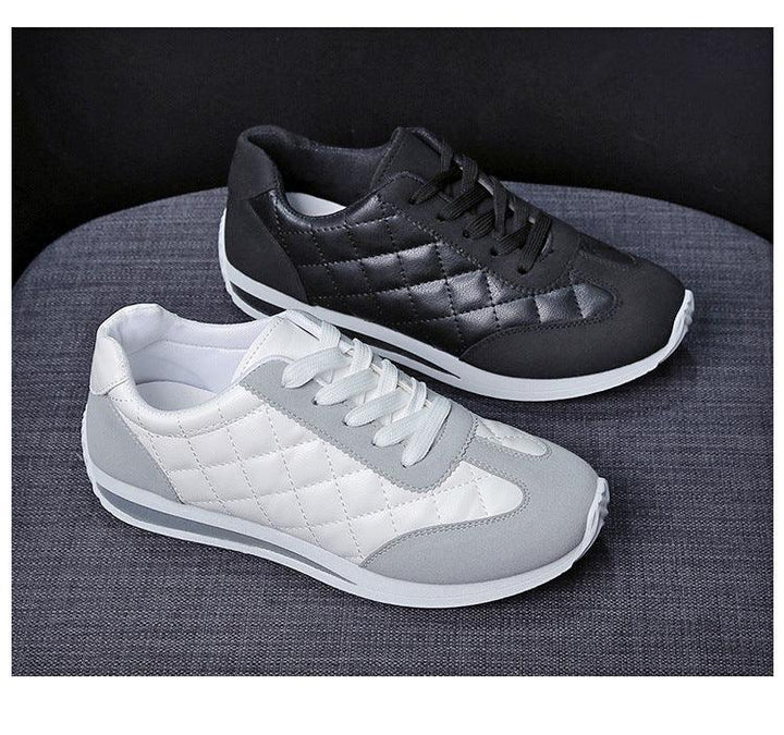 Pair of quilted sneakers, one black and one white with gray accents, on gray fabric surface