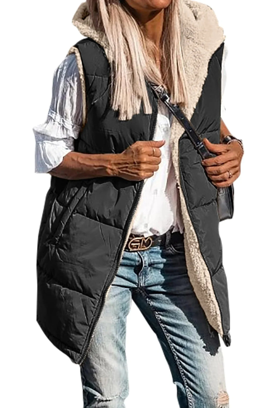 woman wearing black sleeveless padded vest with faux shearling lining, white blouse, and ripped jeans