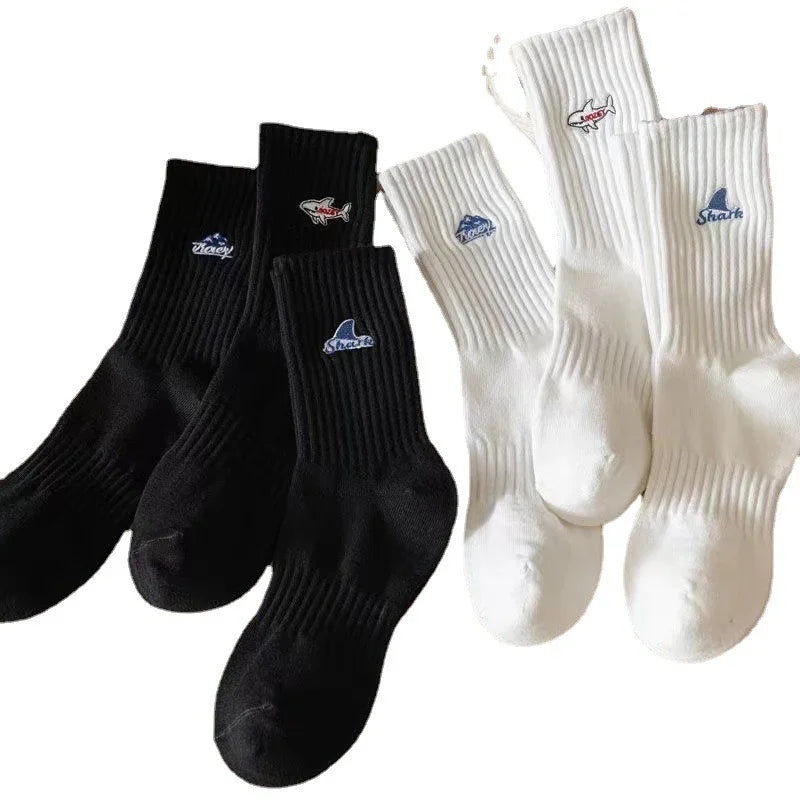 Black and white ribbed crew socks with embroidered shark fin logos in blue and red on each pair