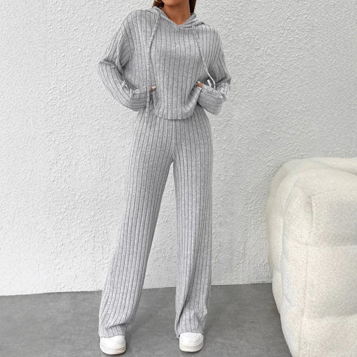 Woman wearing gray ribbed knit hooded sweater and matching wide-leg pants with white sneakers indoors