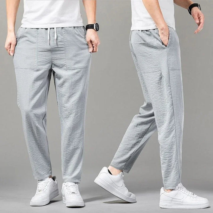 Men's light gray casual jogger pants with pockets, paired with white sneakers and white T-shirt