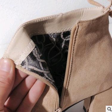Close-up of hand holding beige suede ankle boot with open inner zipper showing patterned fabric lining