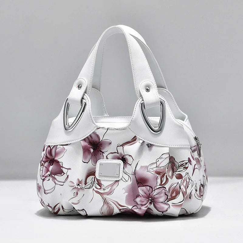 White handbag with purple floral print and double white straps with silver hardware