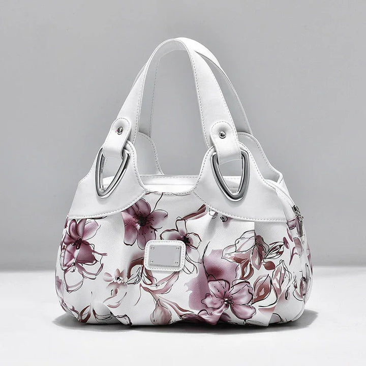White handbag with purple floral print and double white straps with silver hardware