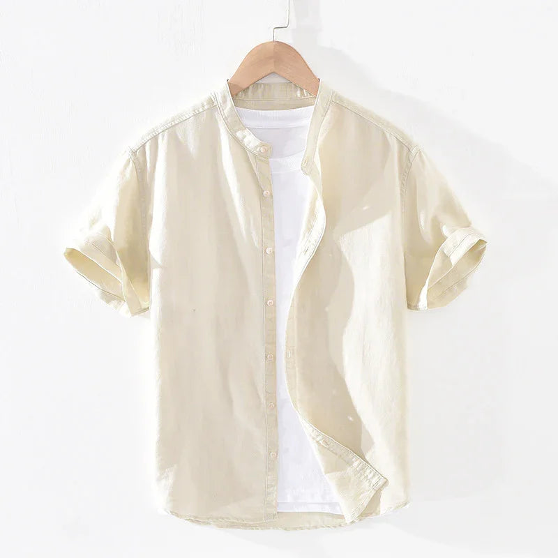 Beige short-sleeve button-up shirt with rolled cuffs over white T-shirt on wooden hanger
