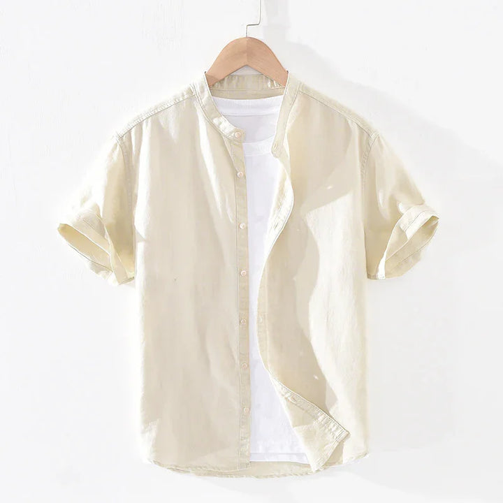 Beige short-sleeve button-up shirt with rolled cuffs over white T-shirt on wooden hanger