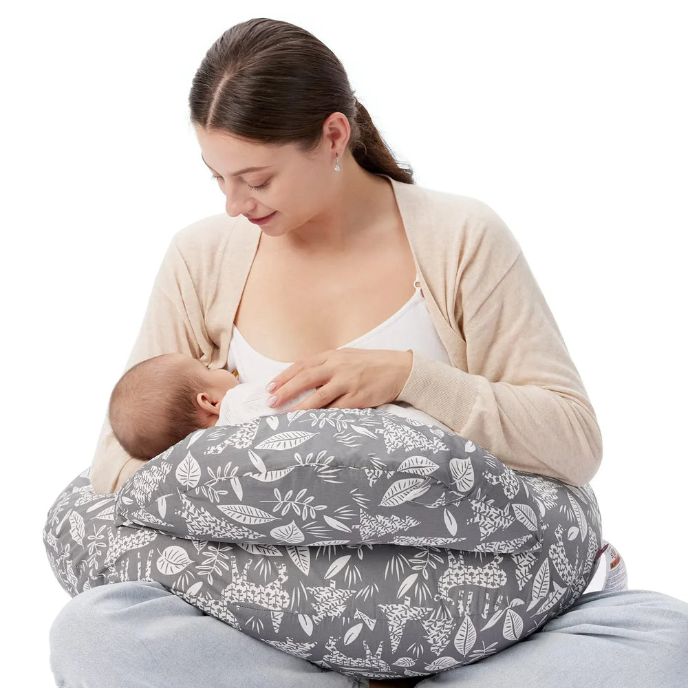 Mother breastfeeding baby using gray floral nursing pillow, both sitting comfortably