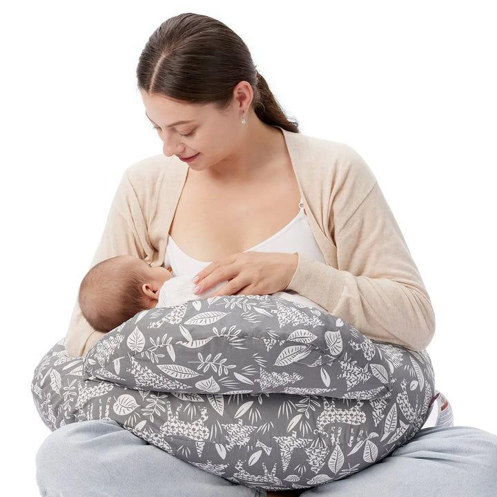 Mother breastfeeding baby using gray floral nursing pillow, both sitting comfortably