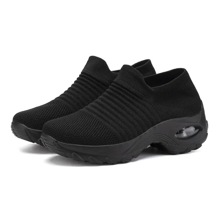 Pair of black slip-on athletic shoes with knitted upper and cushioned thick sole with visible air sole unit