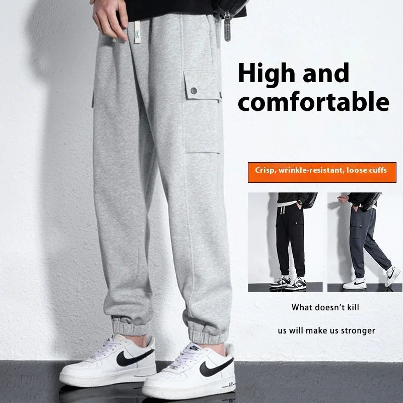 Gray loose cuff sweatpants with side pocket and white Nike sneakers on white textured wall background