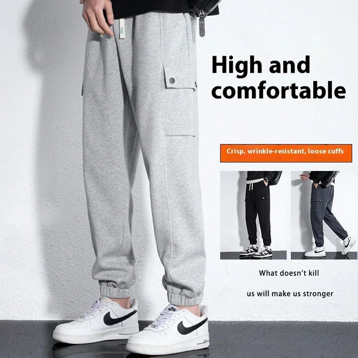 Gray loose cuff sweatpants with side pocket and white Nike sneakers on white textured wall background
