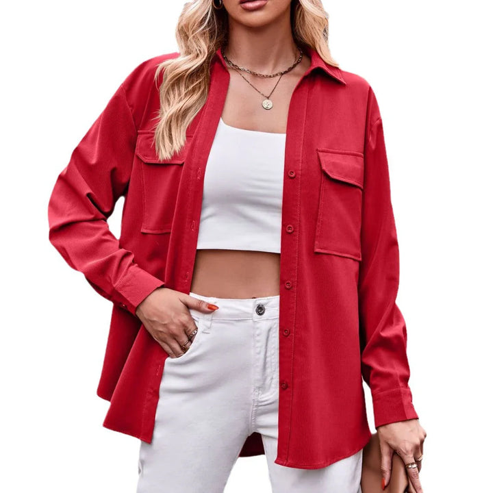 Woman wearing red button-up shirt jacket, white crop top, and white pants with gold necklaces