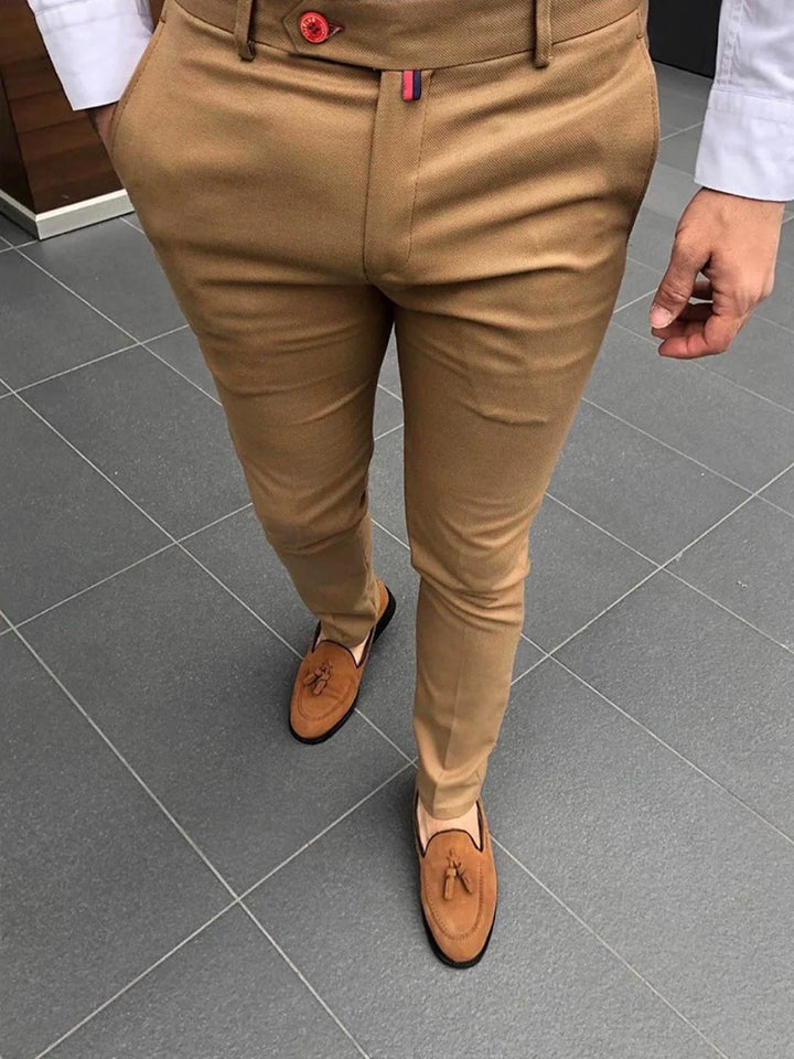 Man wearing slim fit beige trousers and tan tassel loafers on gray tiled floor