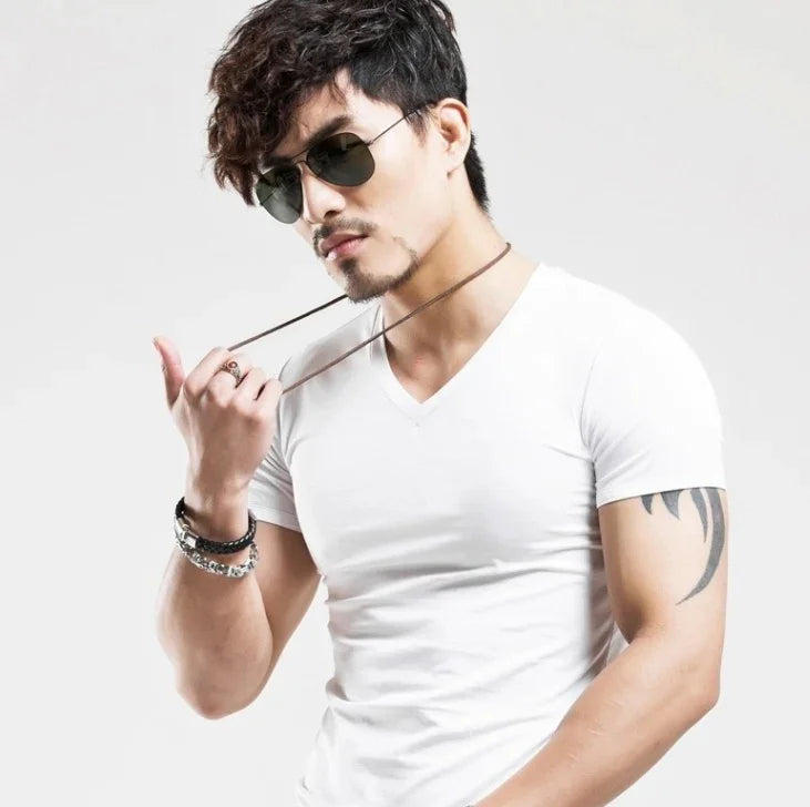 Stylish man in white v-neck t-shirt wearing sunglasses, bracelets, and a tattoo on his arm